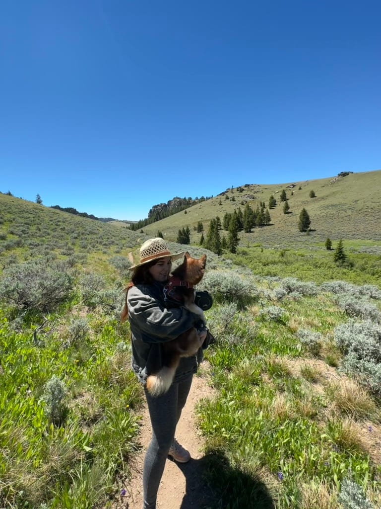 Nichole hiking a green mountain trail carrying their cat